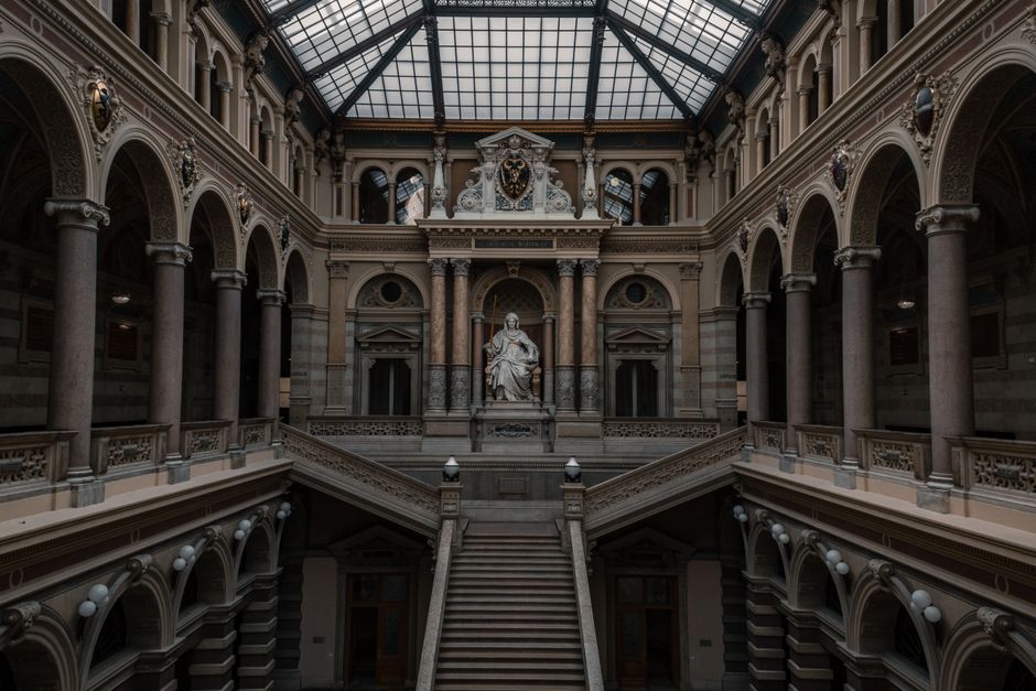 A grand interior with ornate architecture and central statue, showcasing intricate design.