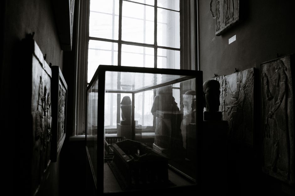 Elegant black and white image showcasing museum interior with sculptures and intricate wall art in soft light.